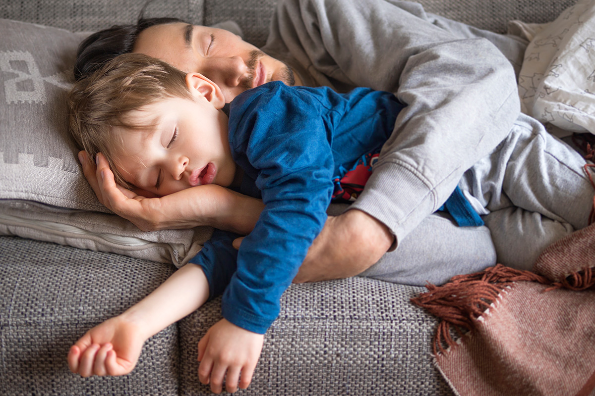 father and son sleeping on couch