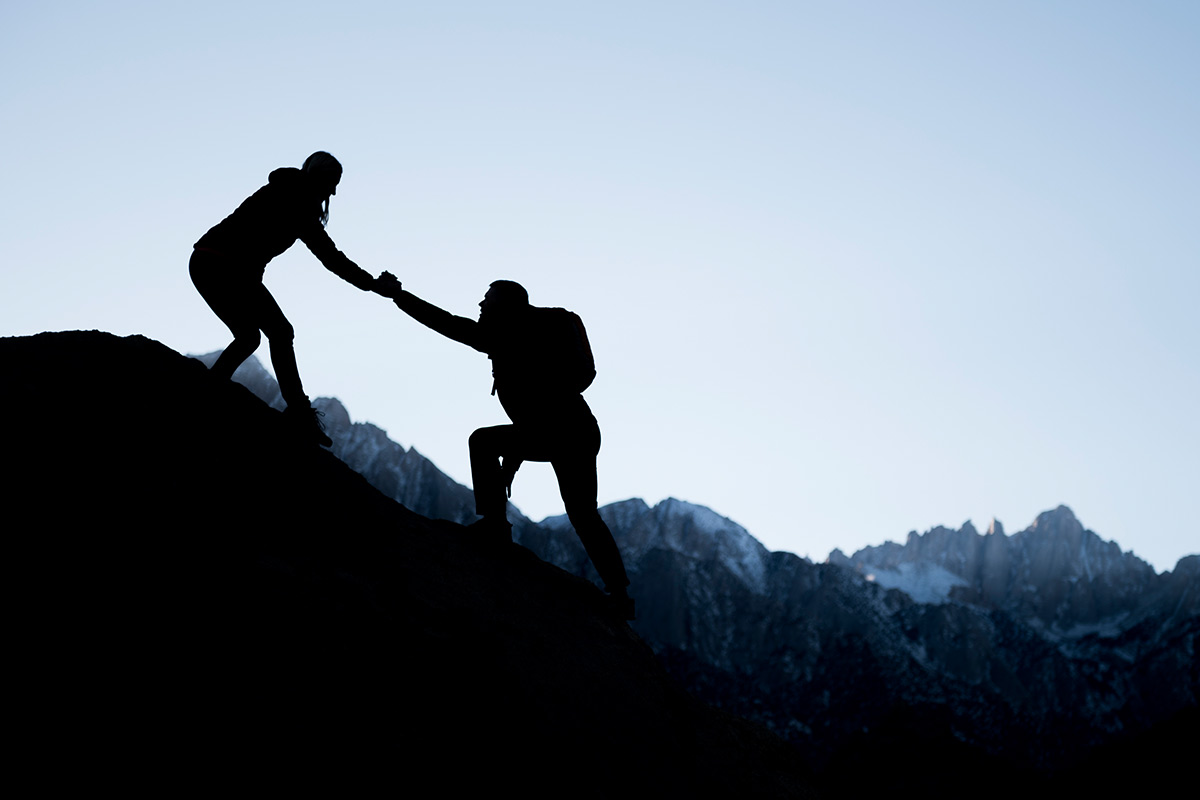 friends helping eachother up a mountain