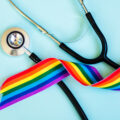 Stethoscope and LGBTQ+ rainbow ribbon pride symbol. Blue background
