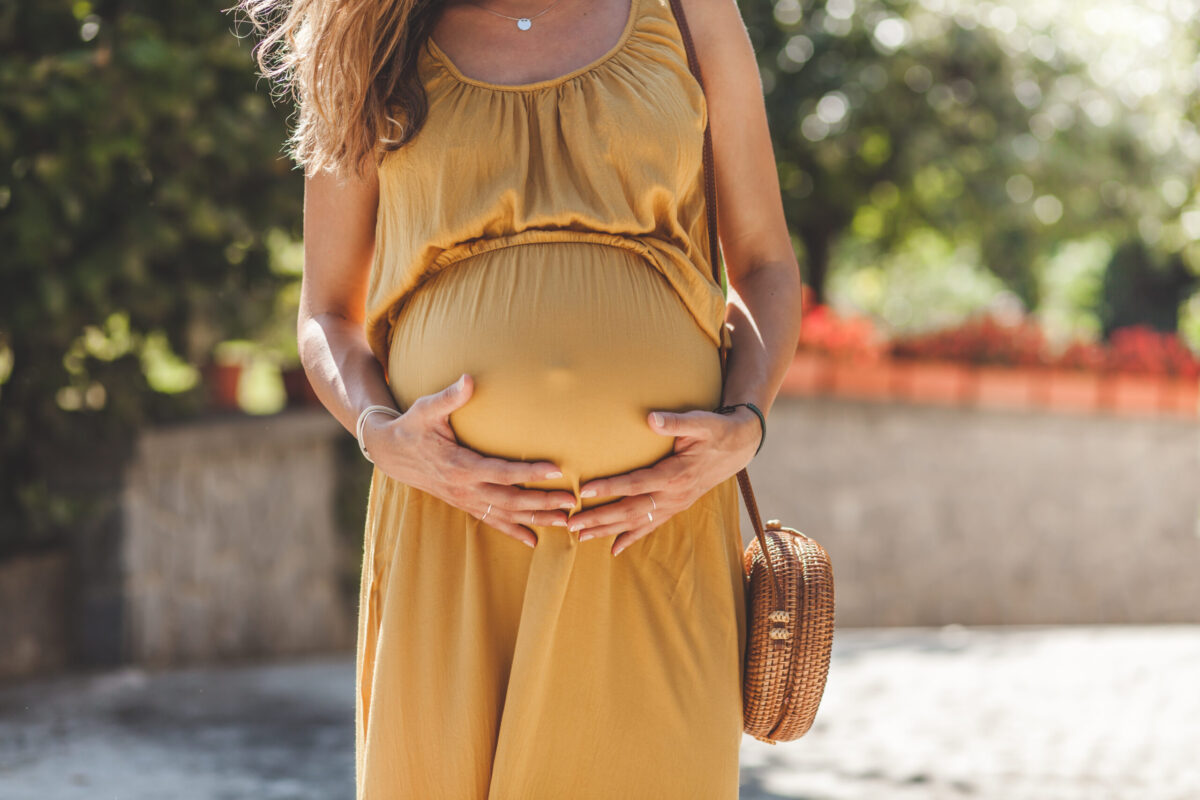 Midsection Of Pregnant Woman Holding Stomach While Standing Outdoors