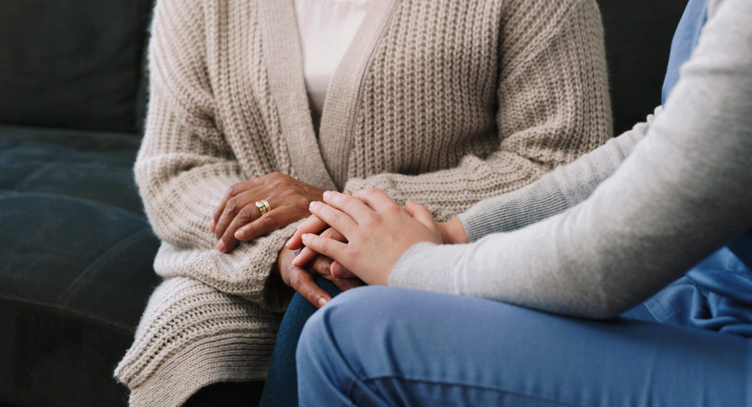 Cropped shot of a nurse holding hands with a senior woman in a nursing home