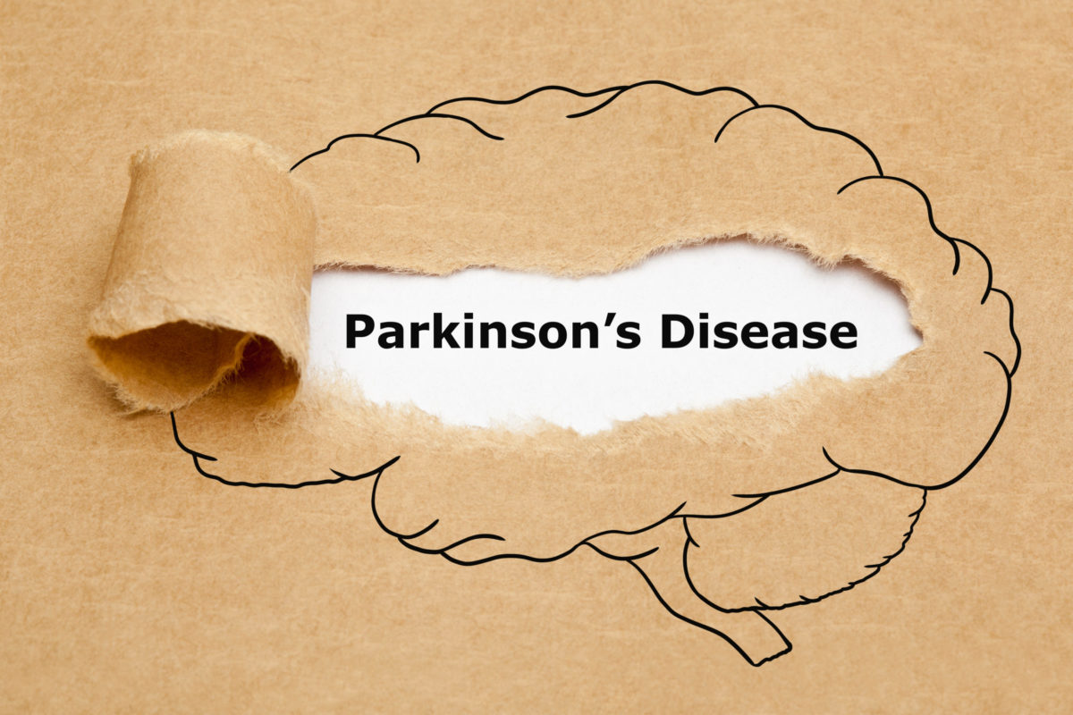 Concept with text Parkinsons Disease appearing behind torn brown paper with human brain drawing.