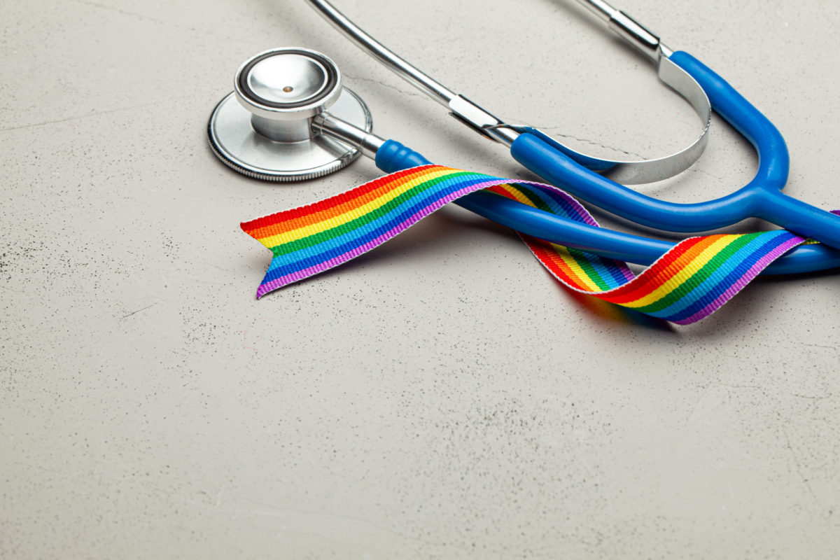 Stethoscope and rainbow ribbon tape. Medical support after sex reassignment surgery. Grey background. Copy space for text