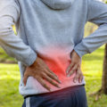 Sport man suffering from backache at park outdoors, Lower back pain concept