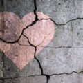 A broken heart. Drawing of a heart on a cracked wall.
