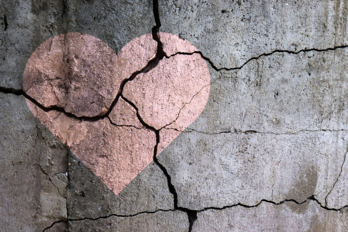 A broken heart. Drawing of a heart on a cracked wall.