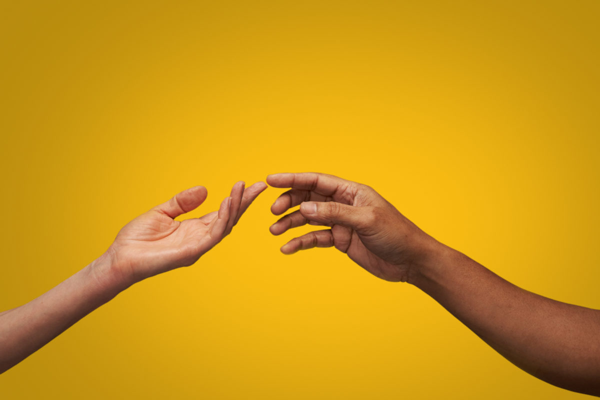 Close up of man and woman touching finger tips in studio with yellow background