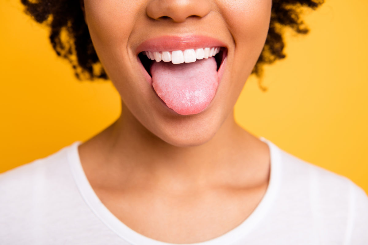Cropped close up photo beautiful amazing she her dark skin lady beaming whitening toothy smile tongue out perfect mouth wear casual white t-shirt isolated yellow bright vibrant background.