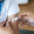 Cropped shot of doctor putting a bandaid on a child's arm after vaccination