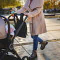 Close up on midsection of unknown woman mother pushing stroller with baby in the city in day motherhood concept