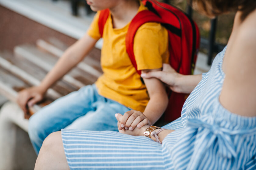 A mother holding her son's hand his reassuring, comforting, and encouraging him.