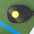 A pickleball paddle and ball on the pickle ball court