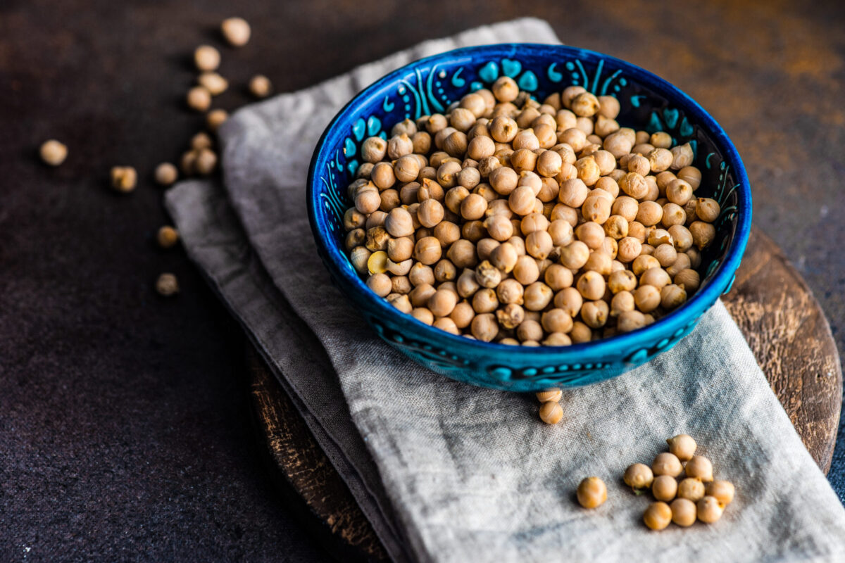 Ceramic bowl full of raw cheakpeas on rustic background with copy space