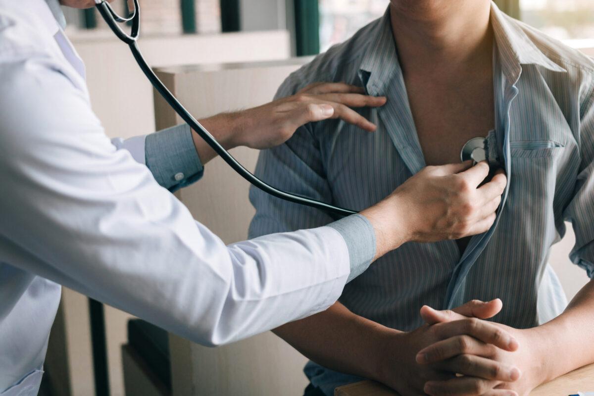 Doctor is using a stethoscope listen to the heartbeat of a male patient.