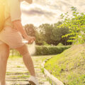 Woman spraying insect repellent on her legs in a public park