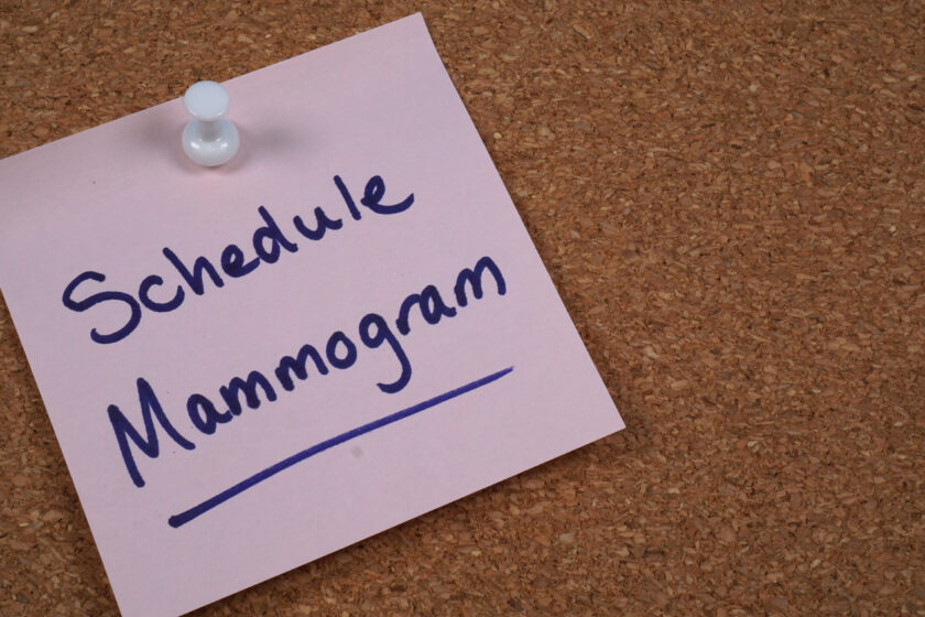 Sticky note reminder to schedule mammogram posted to cork message board.