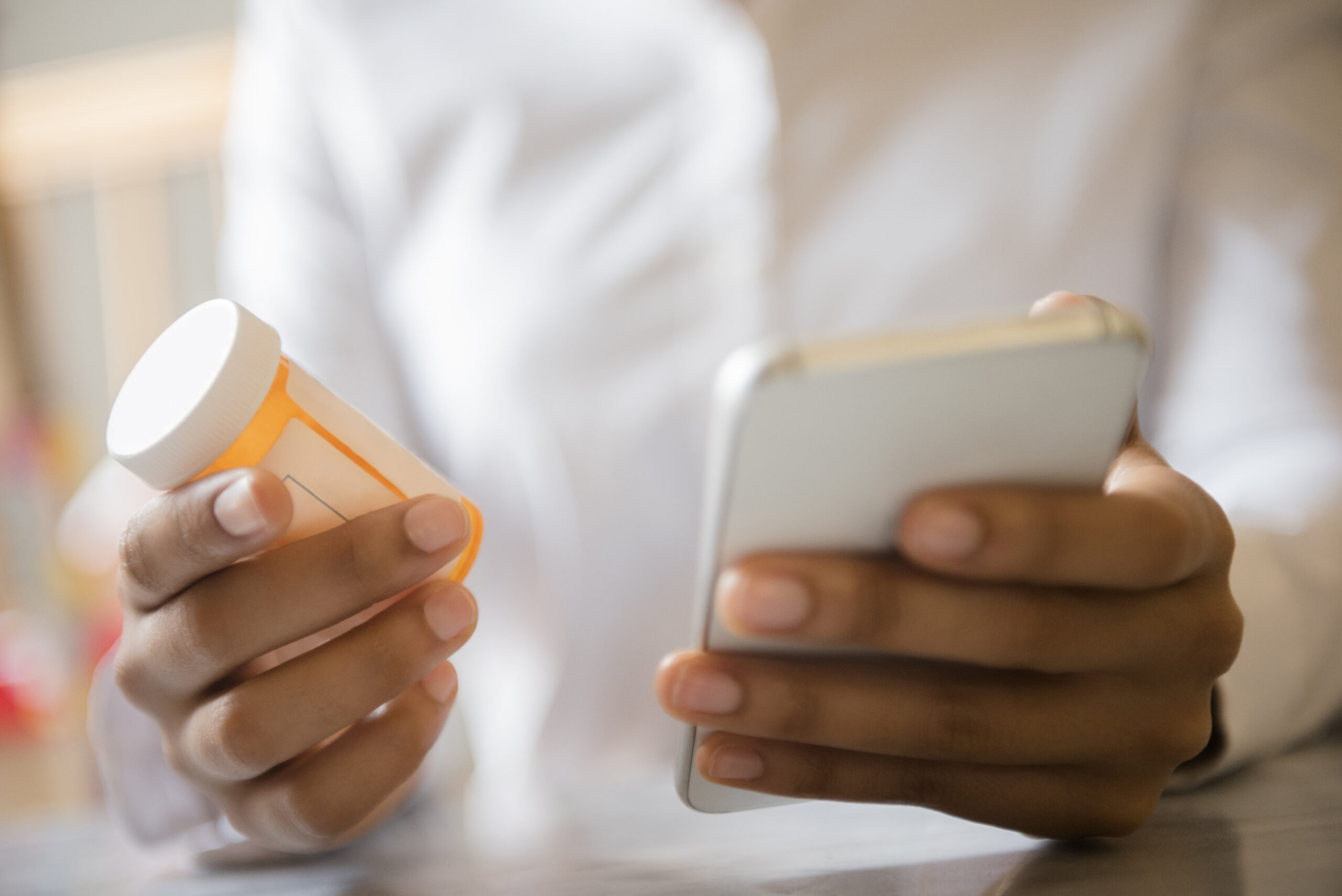 person holding prescription bottle and cell phone