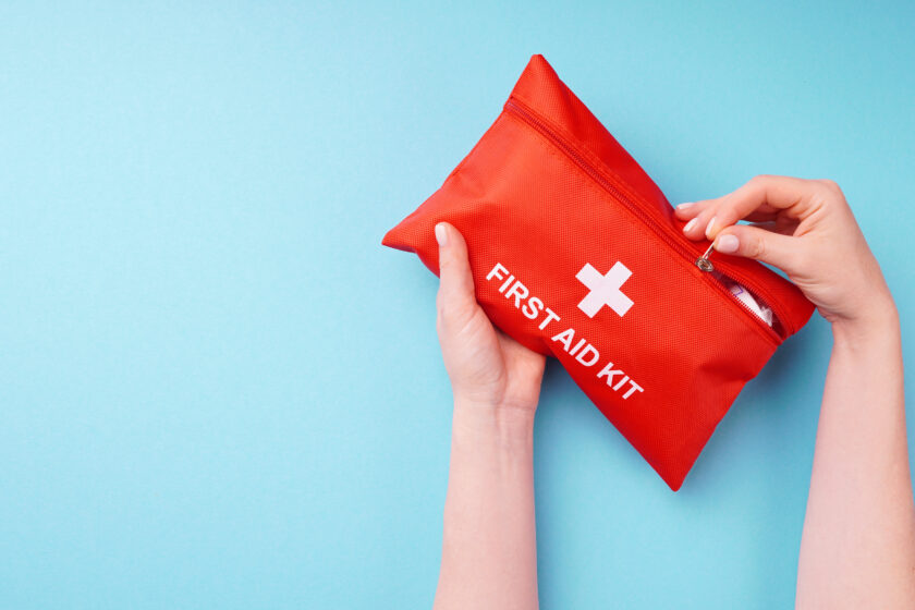 Close-up of a woman's hands holding a fully-equipped first aid kit, ready for providing immediate medical assistance in case of emergencies.