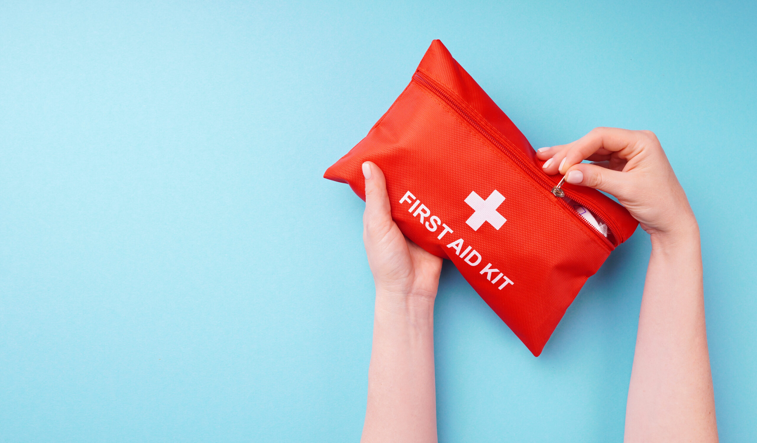 Close-up of a woman's hands holding a fully-equipped first aid kit, ready for providing immediate medical assistance in case of emergencies.