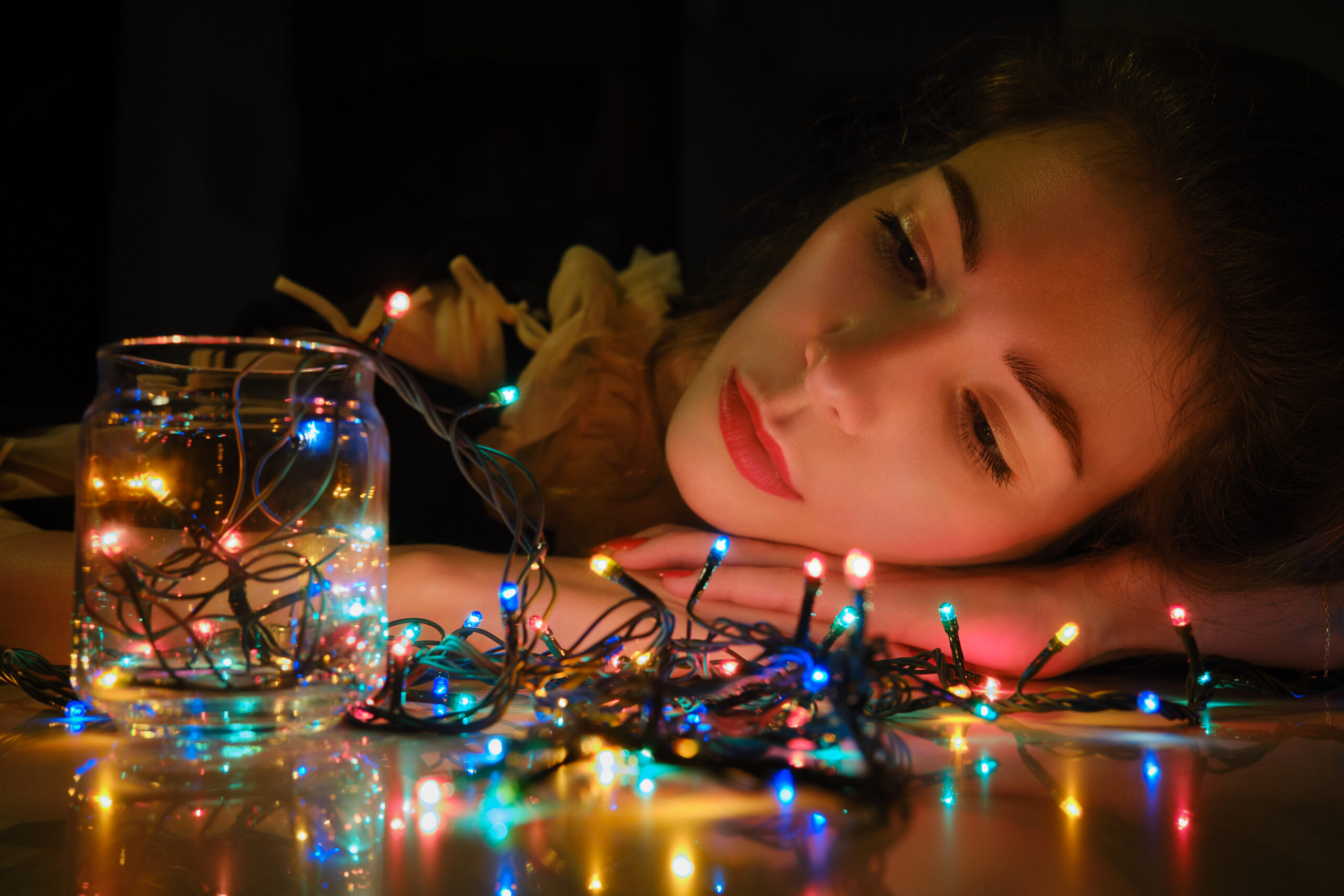 woman with garland of lights experiencing holiday blues