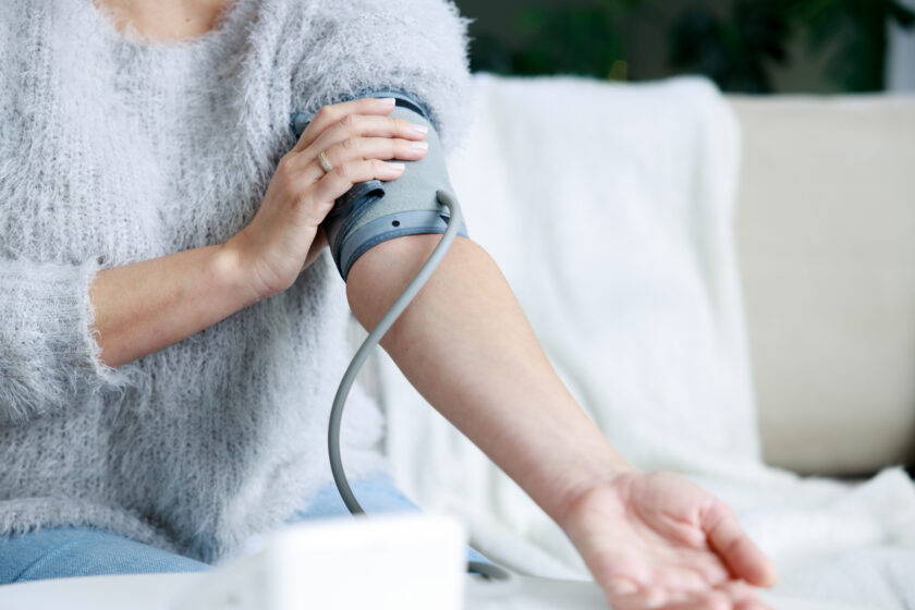 Photo of young woman checking her blood pressure at home