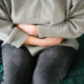 person holding their stomach as if it hurts