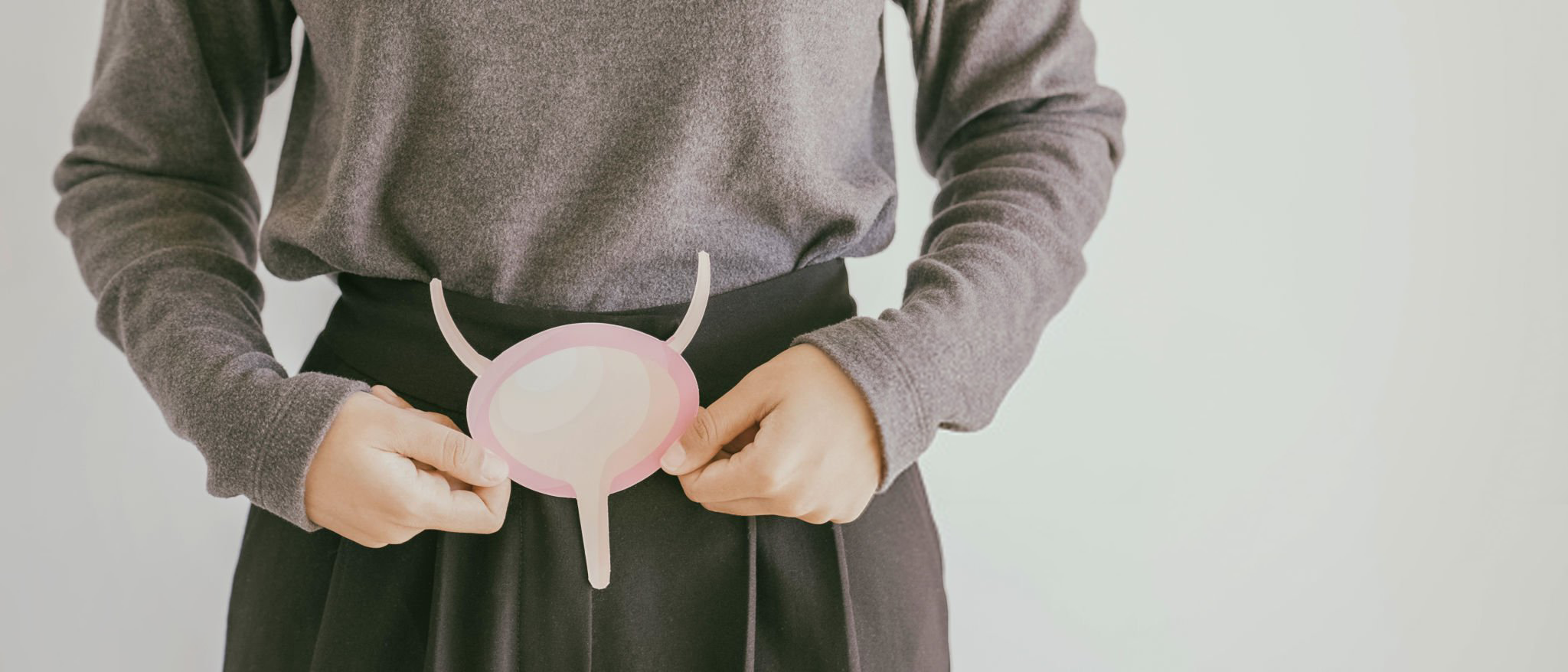 female holding paper cutout representing a bladder in front of her abdomen