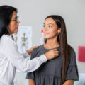 A girl smiles at the woman doctor as she checks her heart.