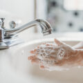 child washing hands with soap in sink
