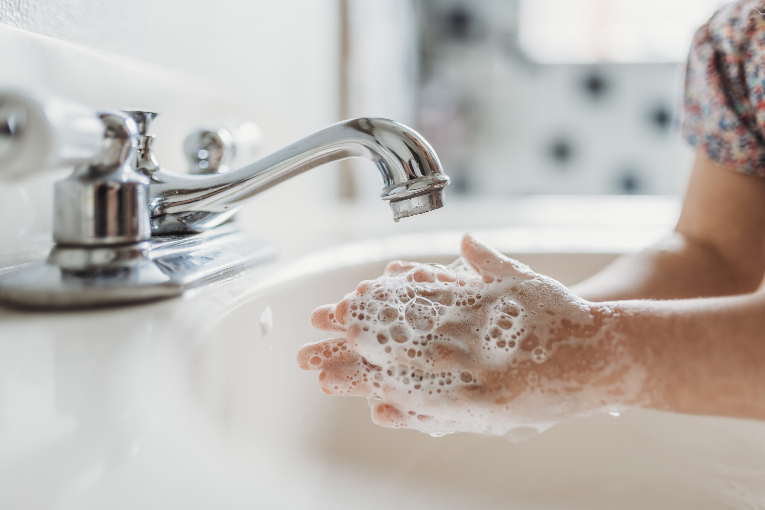 child washing hands with soap in sink