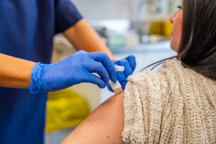 Hands of an unrecognizable nurse injecting the flu vaccine.