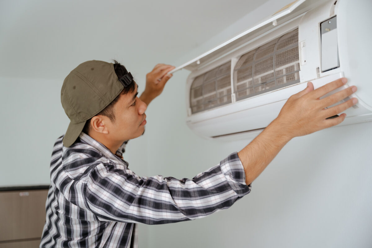 Close-up of A young man inspecting the filter of his air conditioner at home.