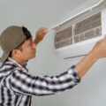 Close-up of A young man inspecting the filter of his air conditioner at home.