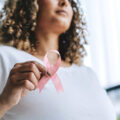 Woman holds ribbon symbolizing breast cancer, pink October