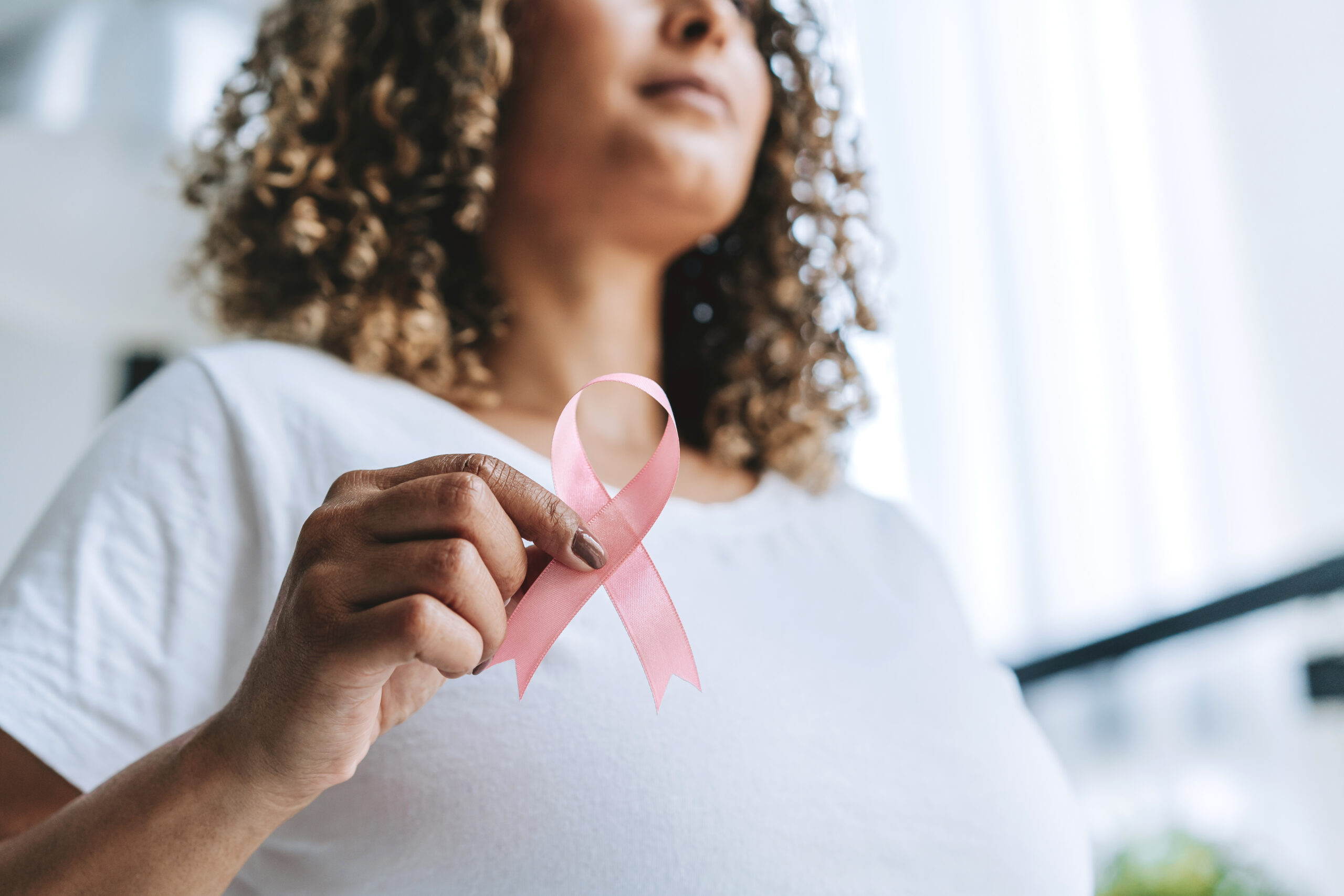 Woman holds ribbon symbolizing breast cancer, pink October
