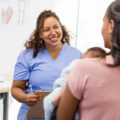 Doctor Talking with Patient and Baby in Medical Clinic
