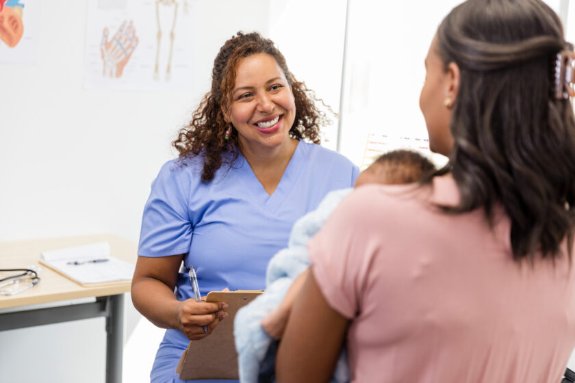 Doctor Talking with Patient and Baby in Medical Clinic