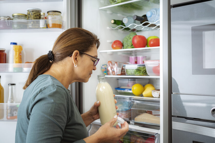 woman smelling milk by the fridge