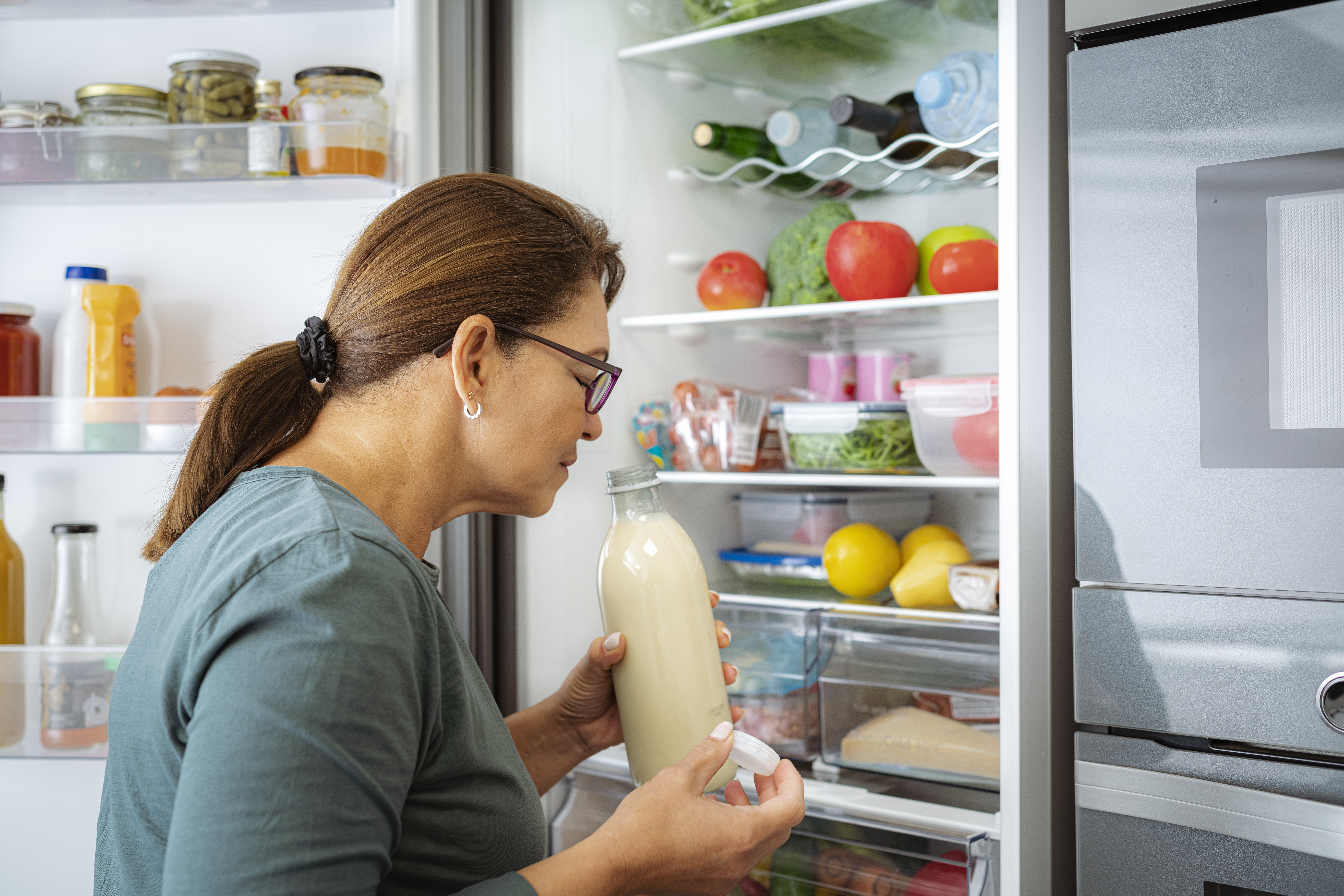 woman smelling milk by the fridge