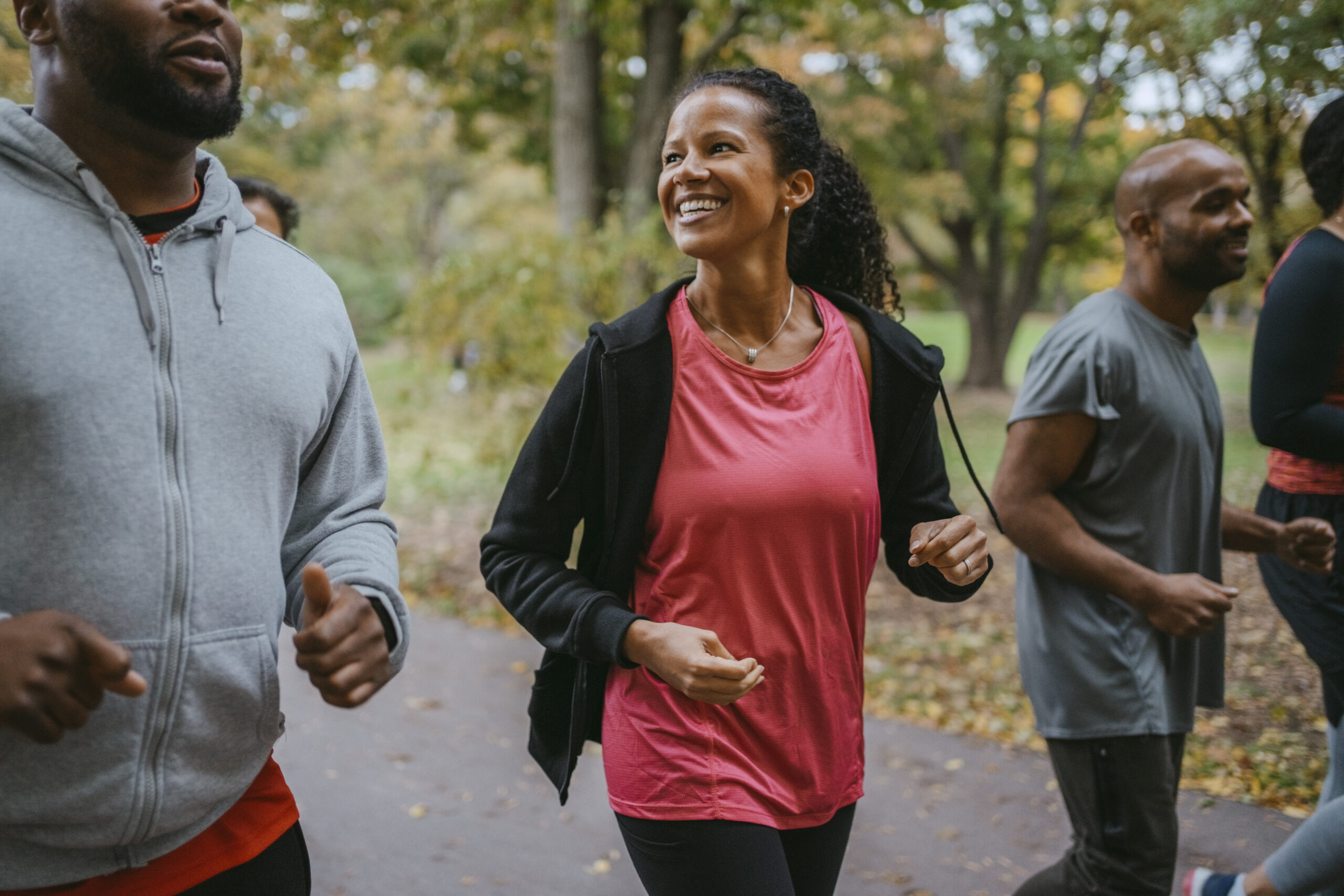 Happy woman talking with male friend while jogging in park