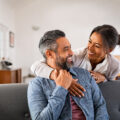 Mature multiethnic couple laughing and embracing at home