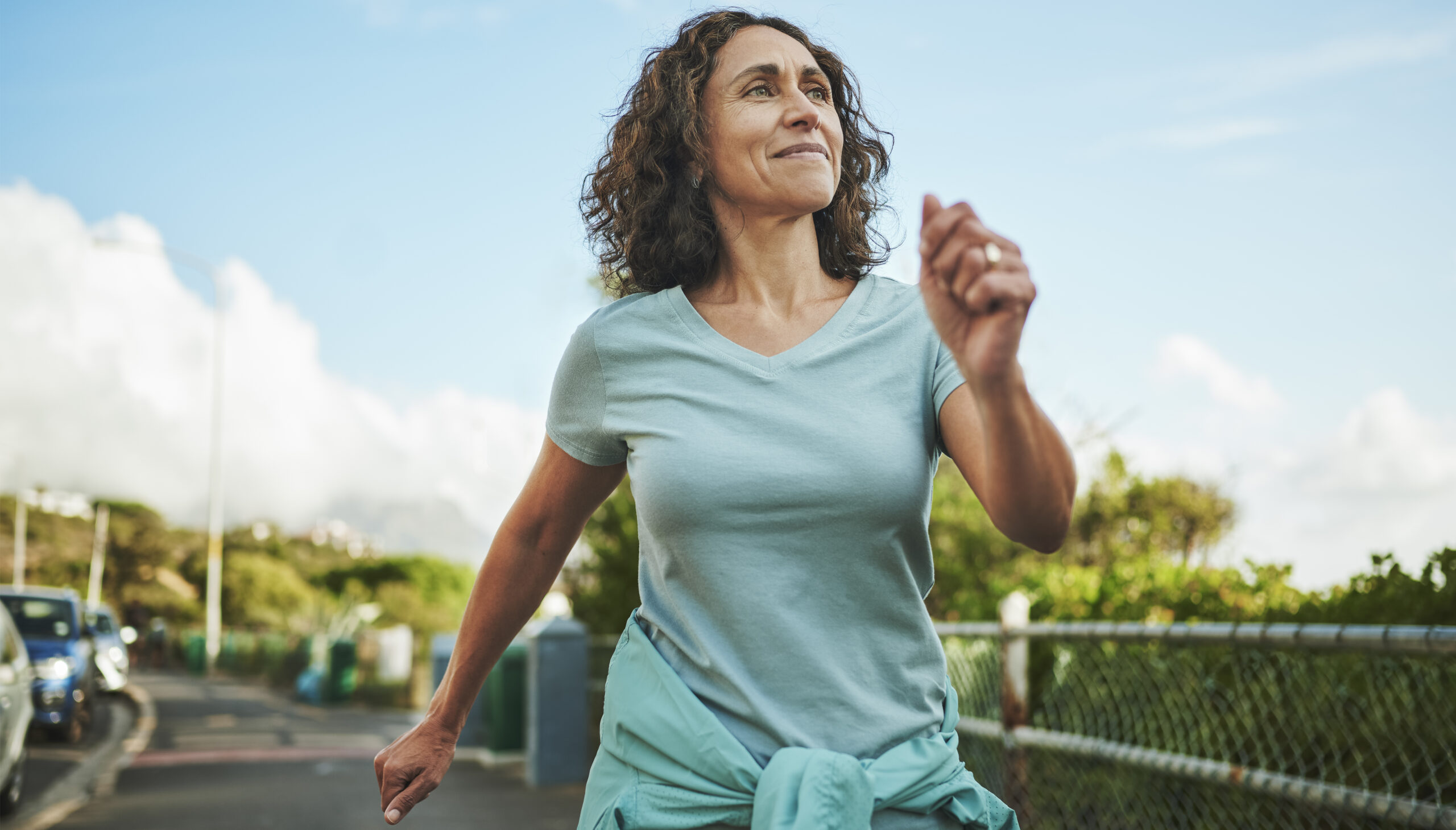 Mature woman in sportswear smiling while out for a power walk