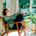 Woman relaxing in armchair by window enjoying daylight