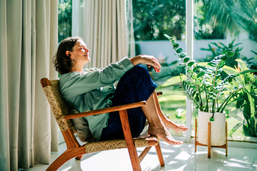 Woman relaxing in armchair by window enjoying daylight