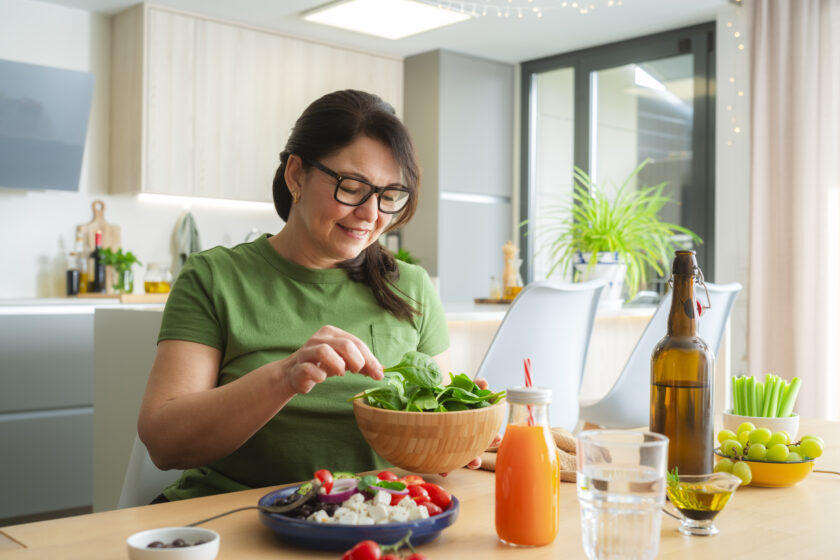 Mature woman eating healthy fresh vegetables meal. Dieting and wellbeing concept