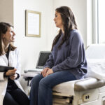 Female doctor discussing treatment with female patient in exam room