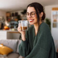 Woman holding a cup of coffee in her living room.
