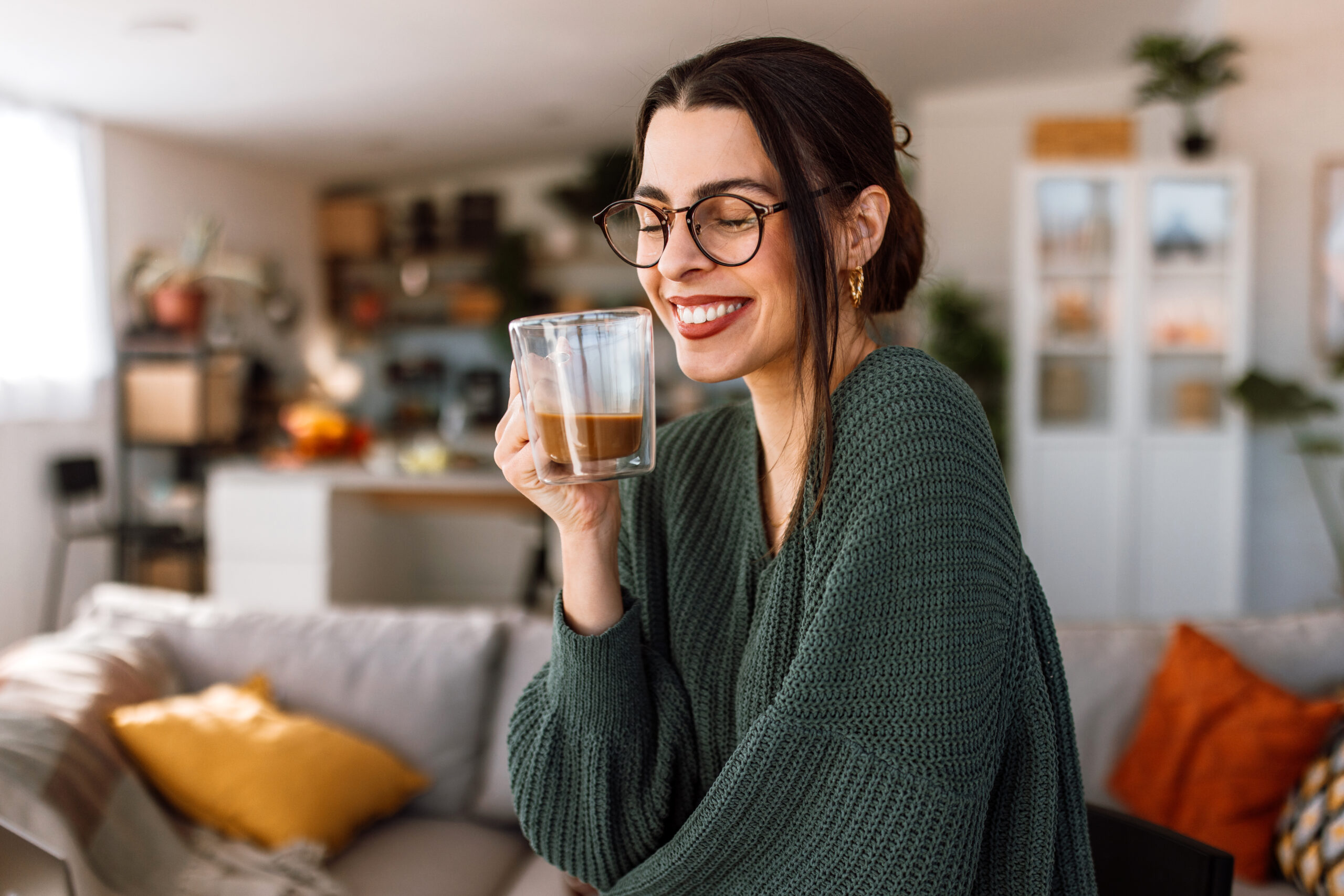 Woman holding a cup of coffee in her living room.