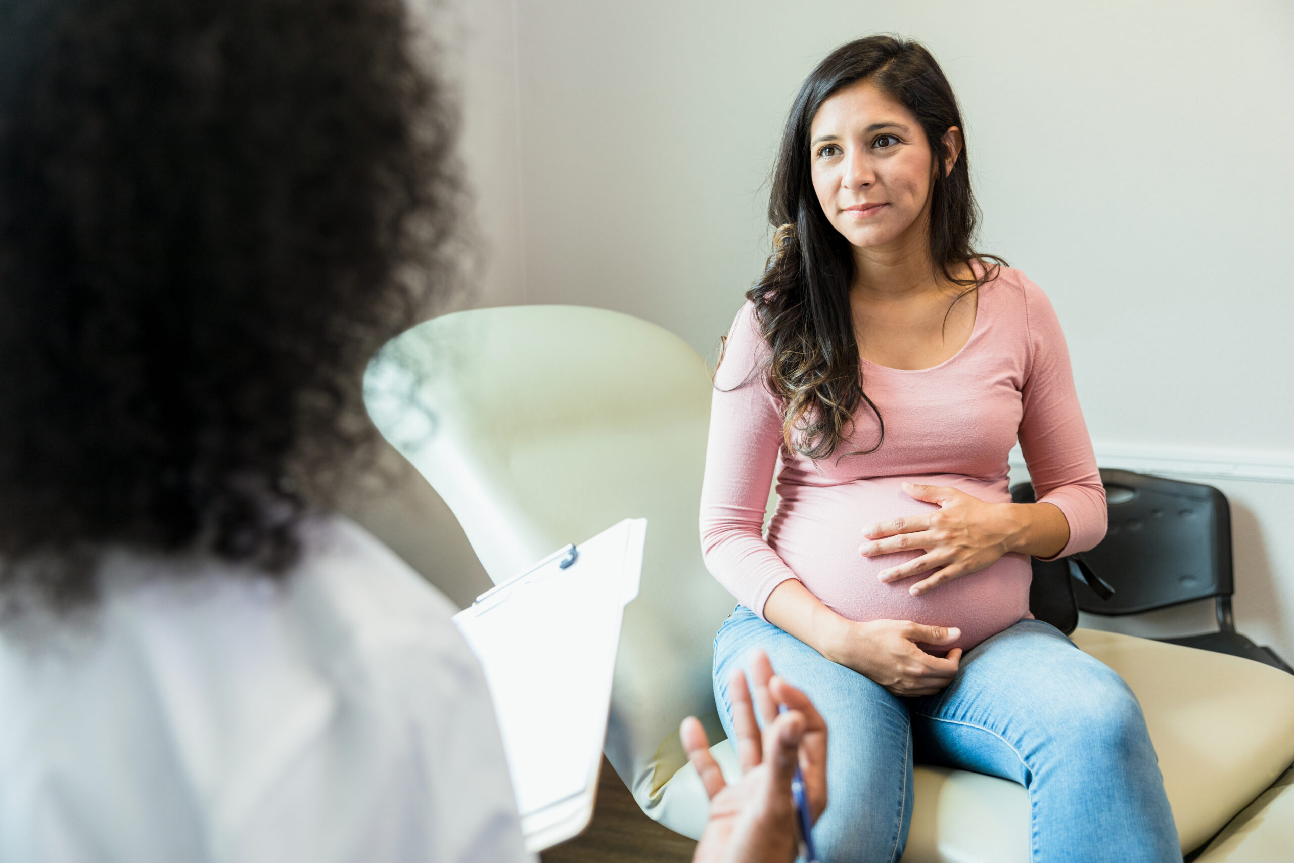 Pregnant woman touches her abdomen in a doctor's office.