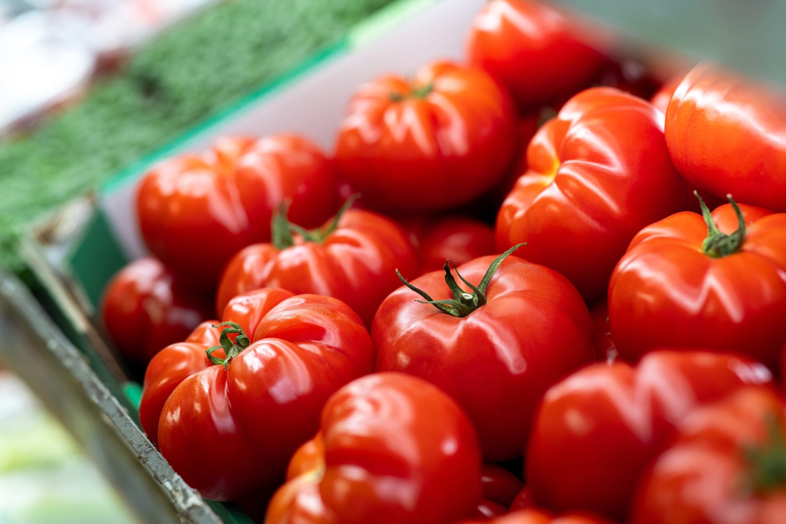 A close-up shot of a crate filled with bright red tomatoes.